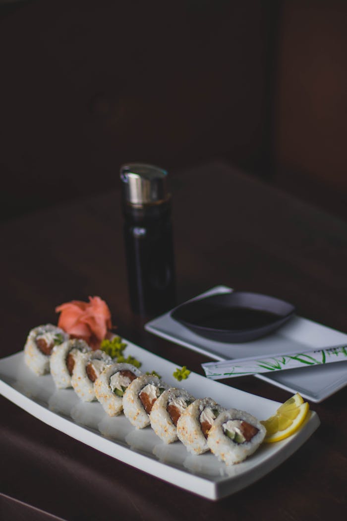Tasty sushi rolls served with soy sauce, ginger, and wasabi on a dark background.