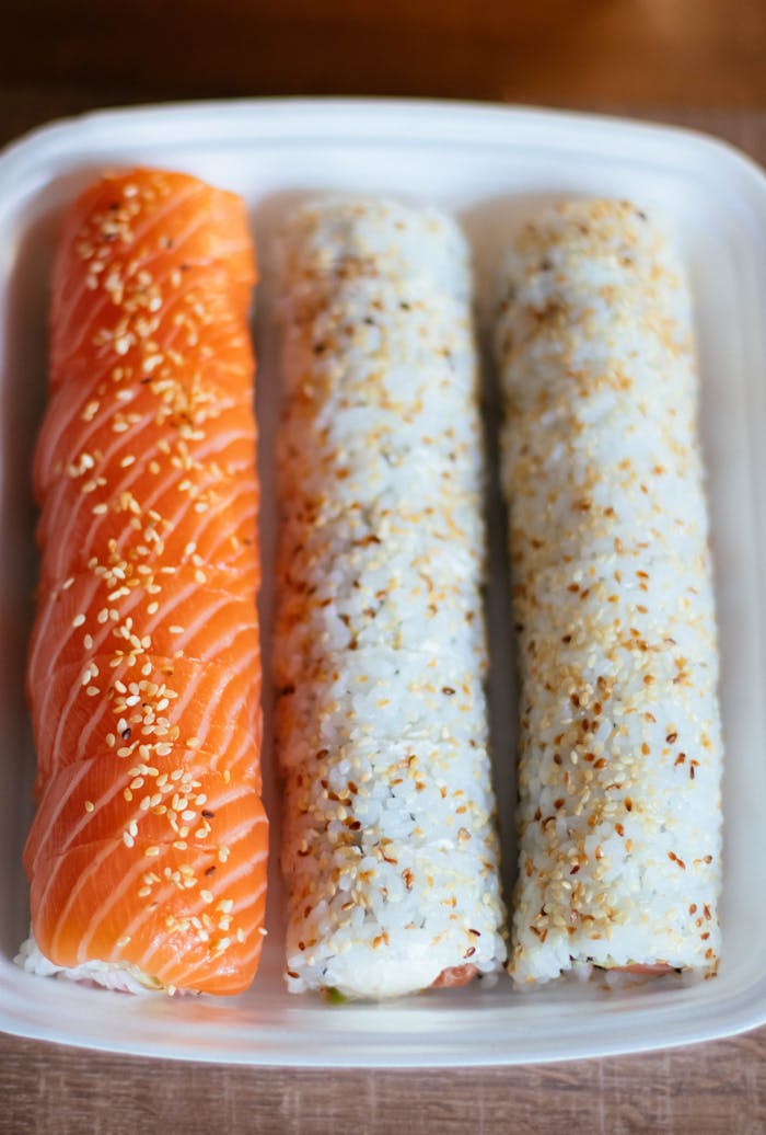 Delicious salmon sushi rolls topped with sesame seeds, perfect for lunch or dinner.