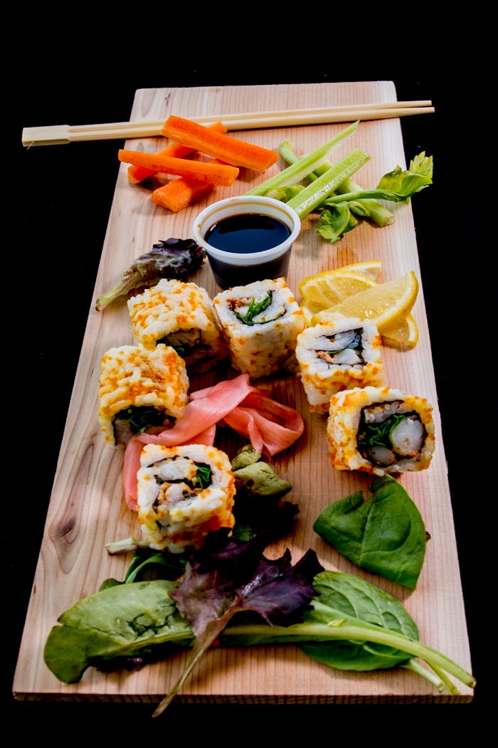 Vibrant sushi platter with fresh vegetables and soy sauce on a wooden board.